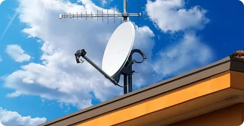 Zestaw anten satelitarnych i naziemnych na dachu domu jednorodzinnego
