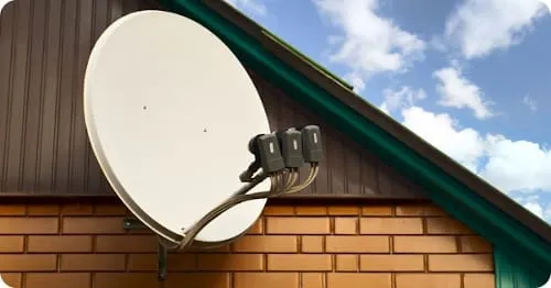Antena satelitarna z trzema konwerterami zamontowana na ścianie domu jednorodzinnego