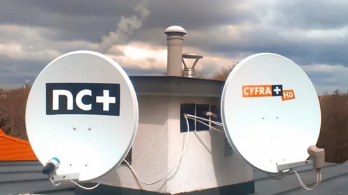 Satelitarne anteny przy kominie Dwie anteny satelitarne z logo CYFRA+ i NC+ zamontowane na dachu do ocieplonego komina z kablami wchodzącymi do kratek wentylacyjnych